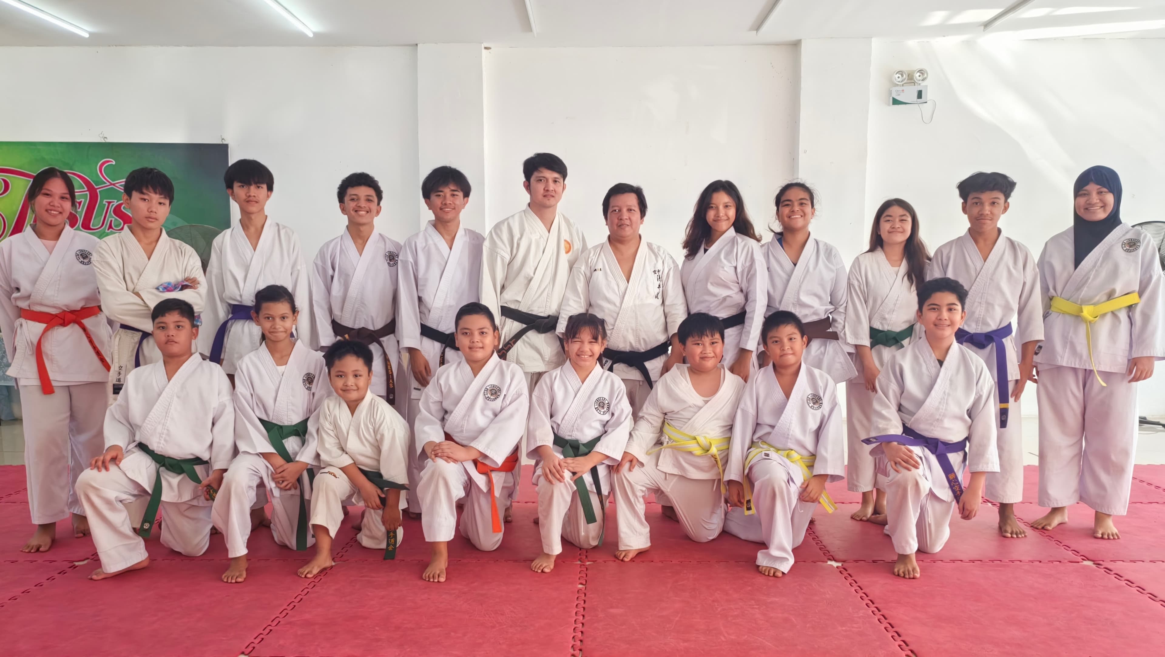 Members of Lionheart Karatedo Club pose for a group photo inside their dojo, representing a range of ages and belt ranks.